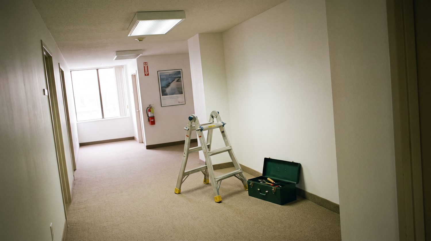 Escabeau et caisse à outils dans un couloir de bureaux, dalle de plafond ouverte